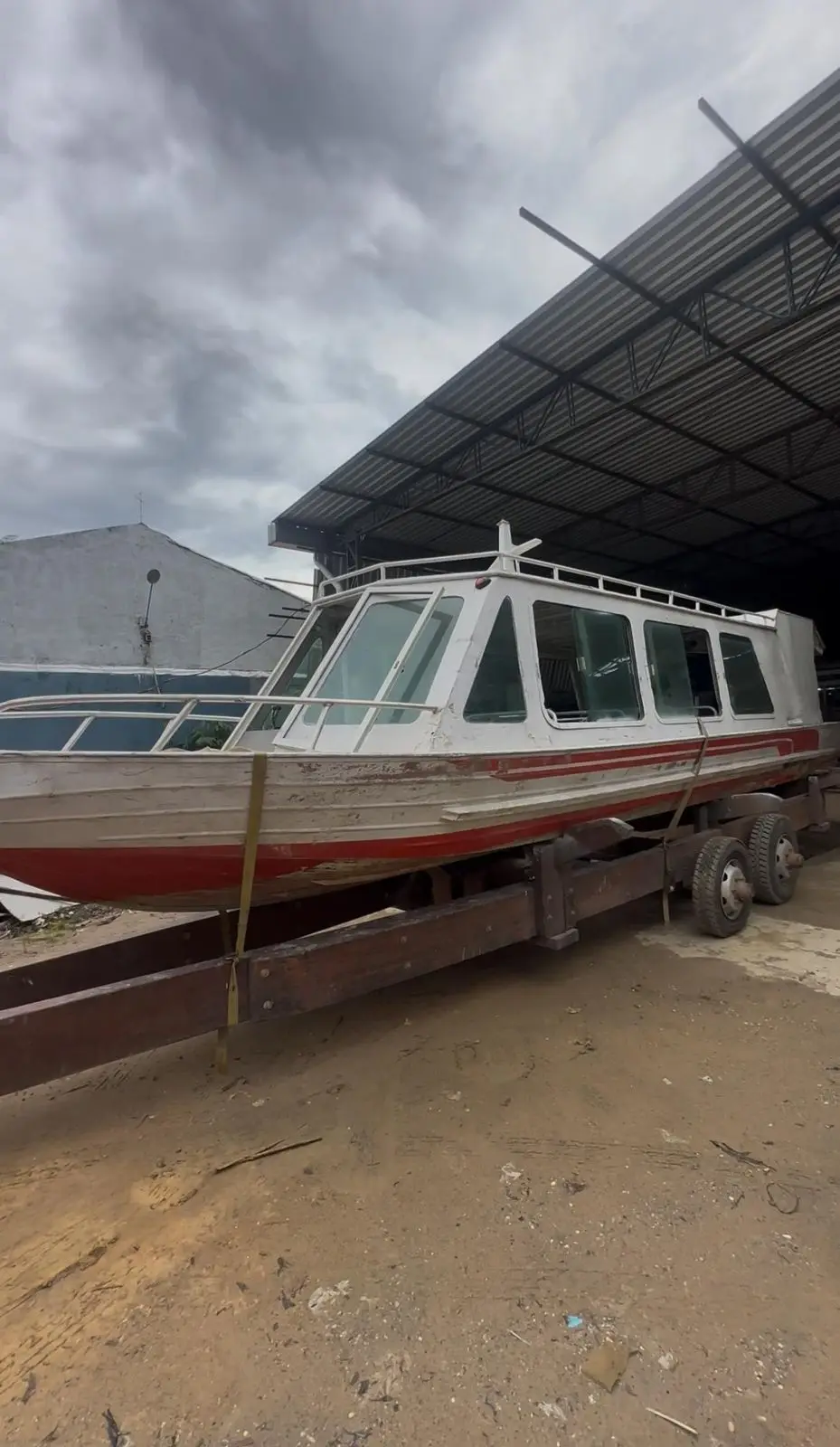 Lancha grande branca com faixa vermelha em reforma estrutural